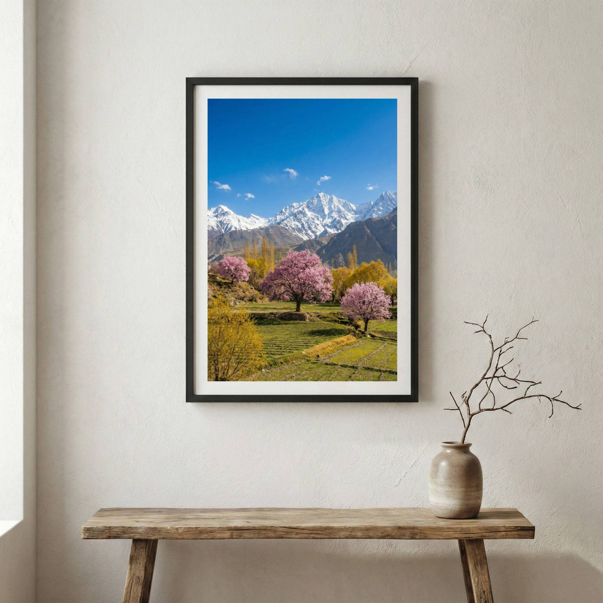 Pink blossom trees in a green meadow beneath snow-capped mountain peaks — wooden frame canvas wall art print, 12×18 in
