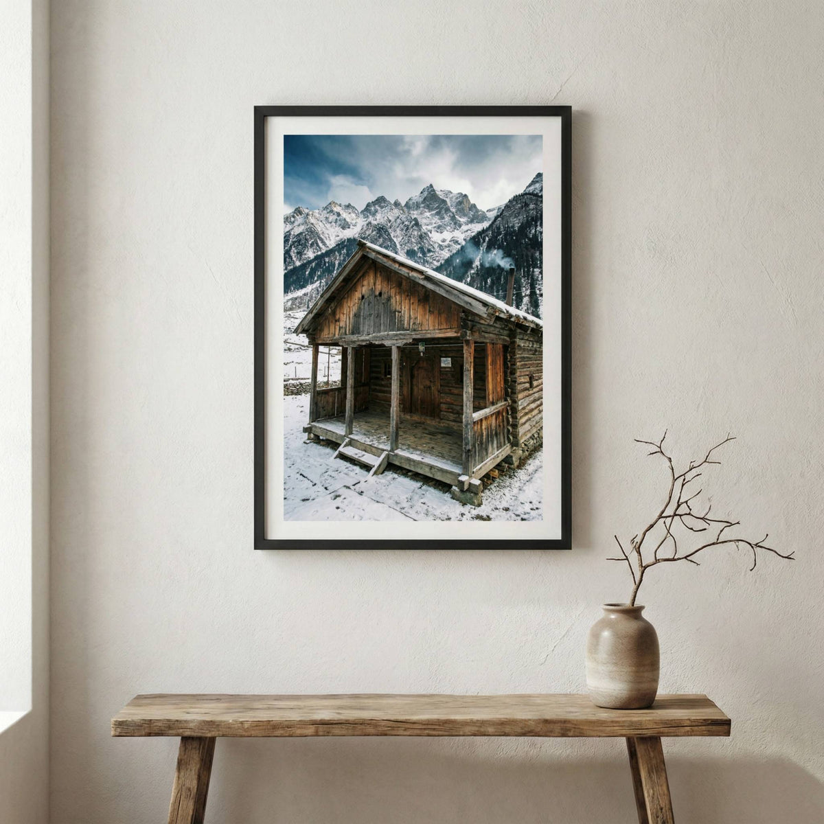 Snow-covered wooden cabin set against jagged, snow-capped mountains — wooden frame canvas wall art print, 12×18 in