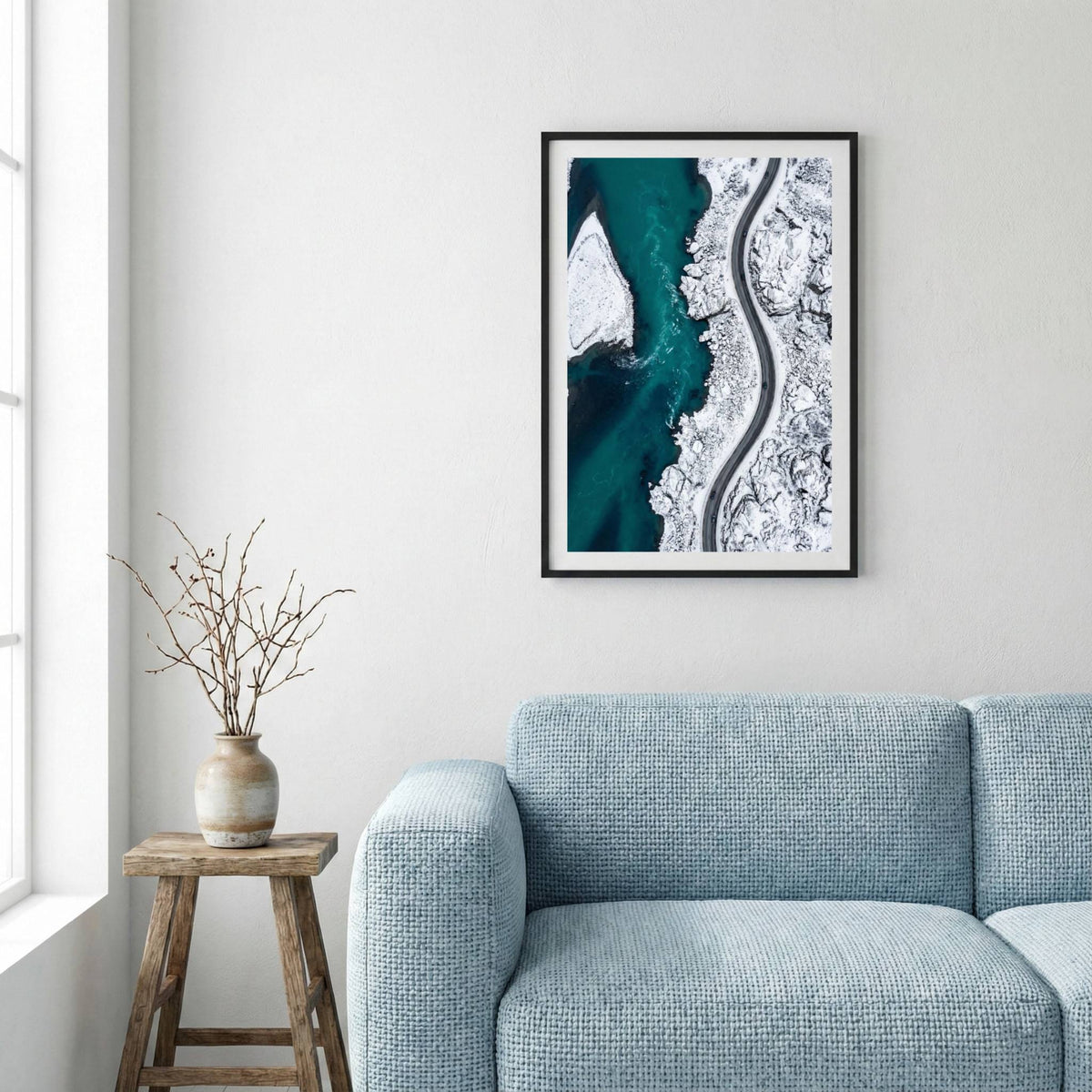 Aerial view of turquoise water meeting a snow-covered coastline and winding road — framed canvas wall art in a wooden frame, 16×24 in