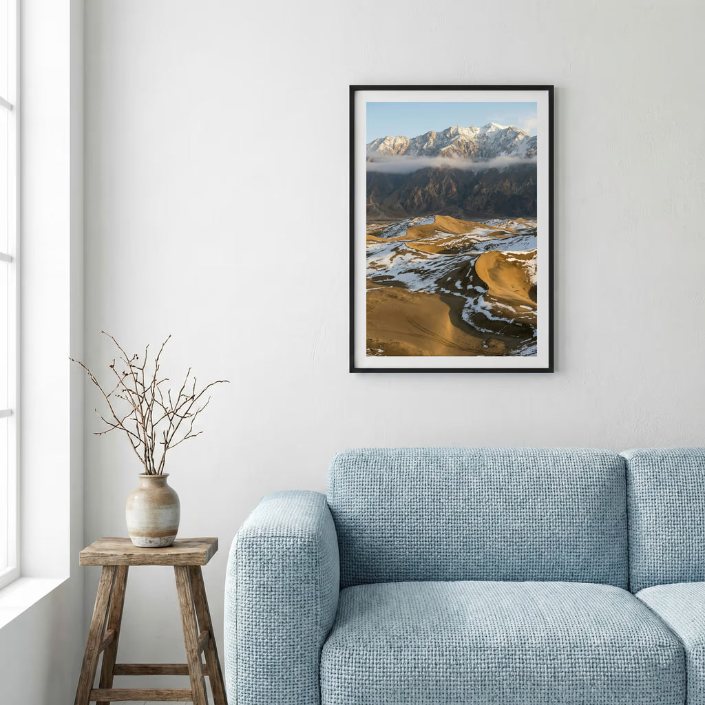 Green river valley with purple wildflowers in the foreground and snow-capped peaks beyond — framed canvas wall art in a wooden frame, 16×24 in