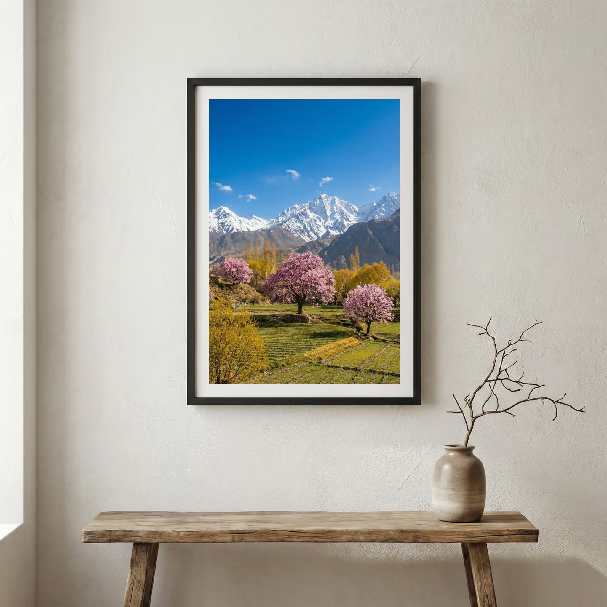 Pink blossom trees in a green meadow beneath snow-capped mountain peaks — wooden frame canvas wall art print, 12×18 in