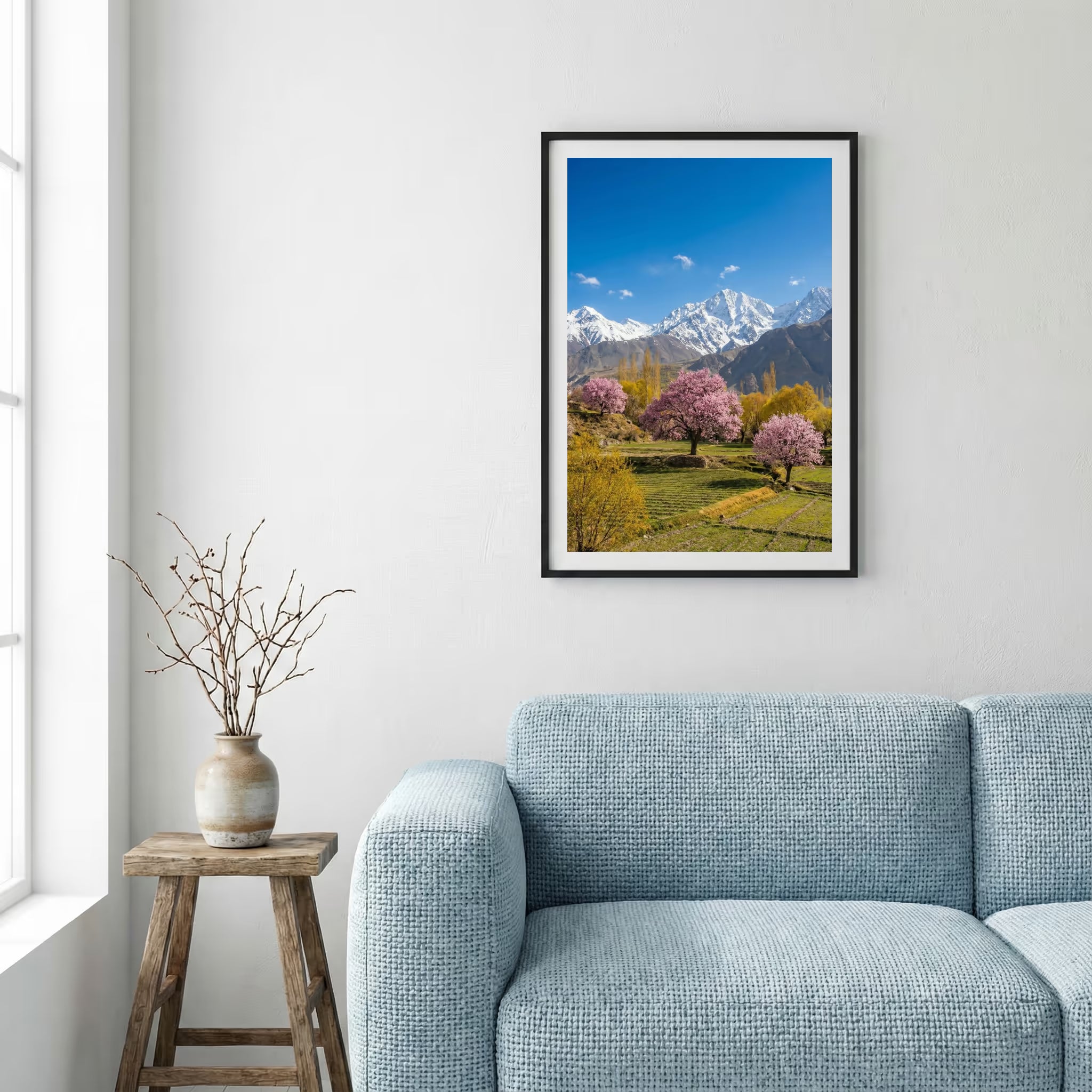 Pink blossom trees in a green meadow beneath snow-capped mountain peaks — framed canvas wall art in a wooden frame, 16×24 in